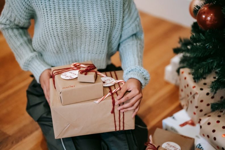 Фото <a href="https://www.pexels.com/photo/crop-woman-with-pile-of-present-boxes-for-christmas-holiday-6347662/" target="_blank">Pexels</a> что подарить девушке на новый год 2026